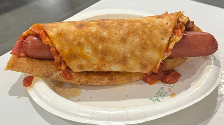 A 1/4 pound Costco hot dog wrapped in a slice of cheese pizza, crust facing out