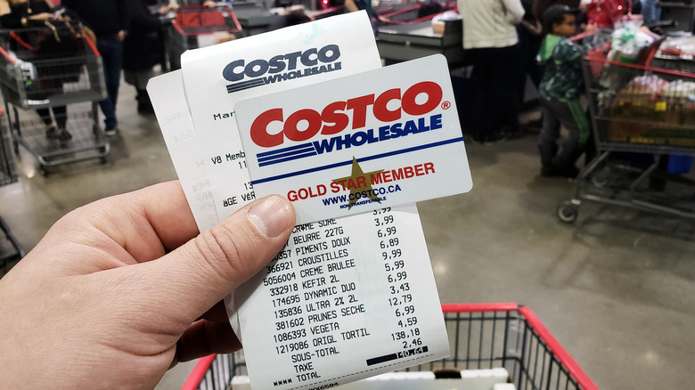 Costco shopper holding up membership card and receipt