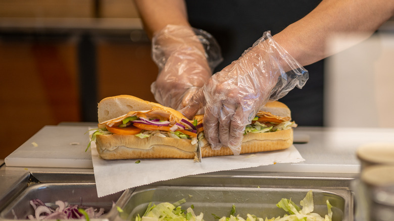 Worker slicing sandwich at Subway