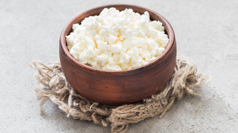 Cottage cheese in a wooden bowl on top of ripped string