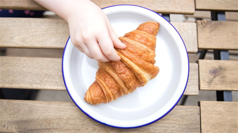 Child's hand on croissant
