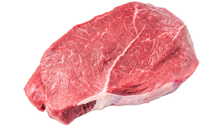 A large piece of raw sirloin steak on a white background