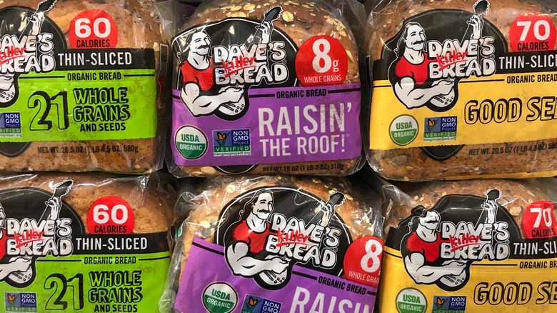 A variety of stacked Dave's Killer Bread loaves on a store shelf