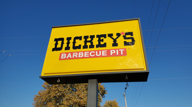 A sign for Dickey's Barbecue Pit in front of a blue sky