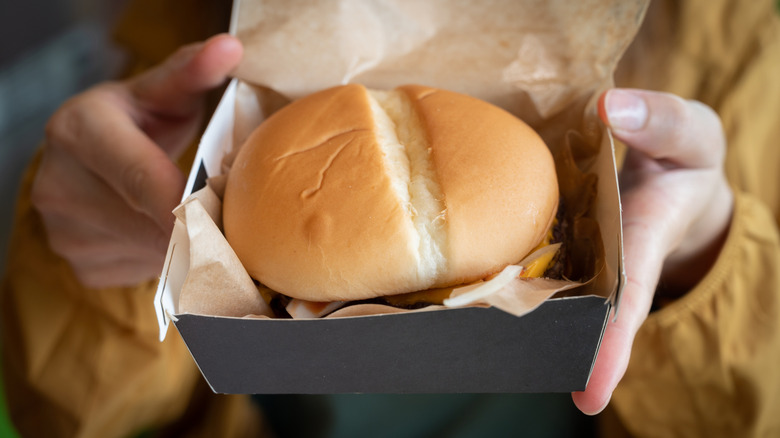 A cheeseburger in a black paper box