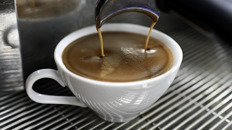 Espresso shots pouring into a mug of coffee