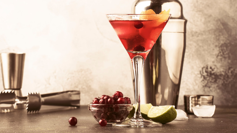 Red cocktail with cranberry, lime, and orange garnishes