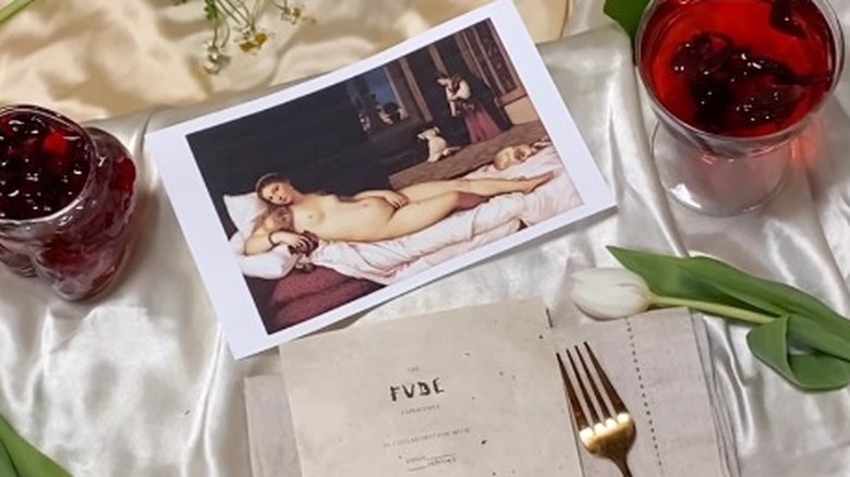 Two drinks on a table with a Renaissance painting 