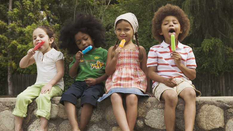 Kids eating popsicles on a stone wall