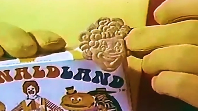 A closeup of Ronald McDonald holding a McDonaldland cookie shaped like him