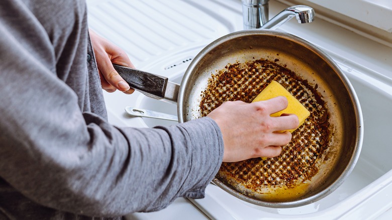 Person scrubbing greasy cookware