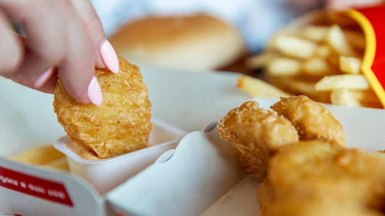 Hand dipping chicken nuggets