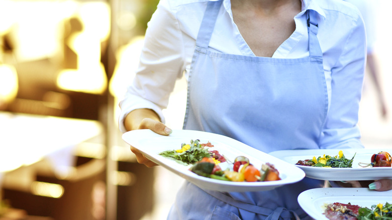Server carrying dishes at restaurant