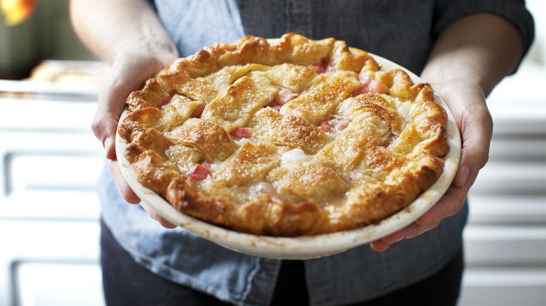 person hands holding a homemade pie in a kitchen