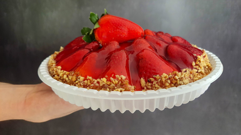 person holding a pie in a white plastic reusable pie container