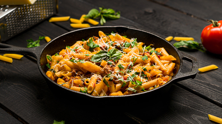 Penne rigate pasta cooked in cast iron pan with meat sauce