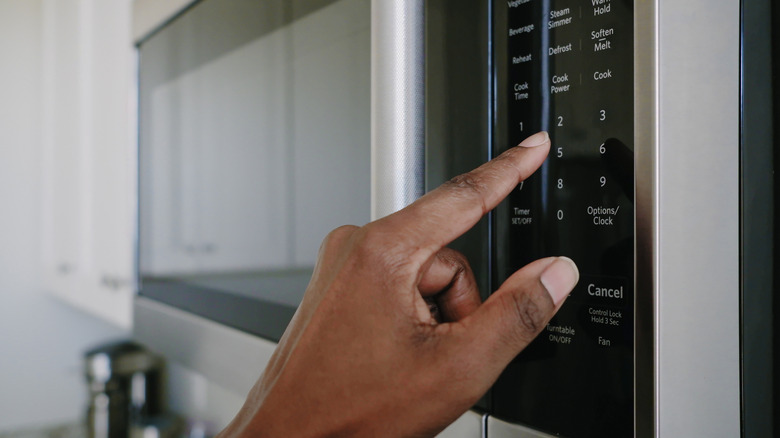 Person pressing microwave buttons