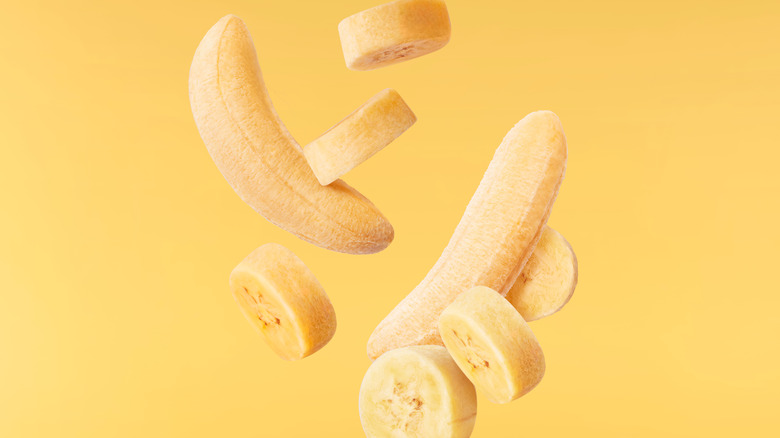 Peeled bananas suspended against a yellow background