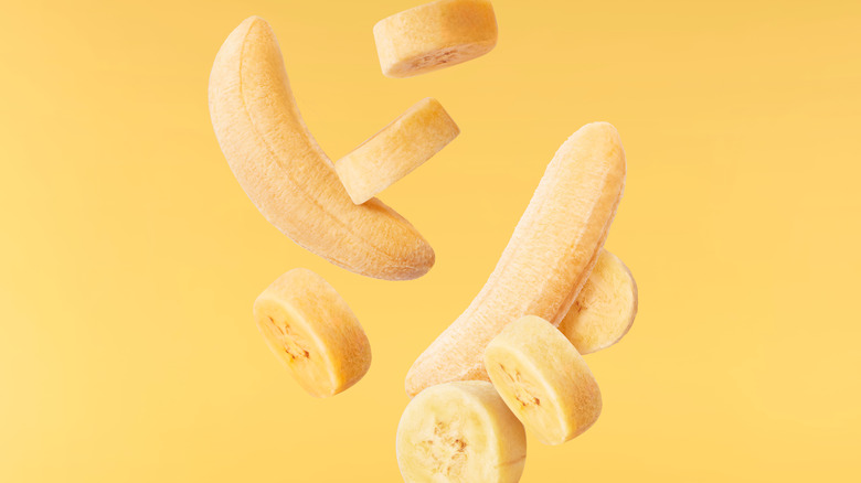 Peeled bananas suspended against a yellow background