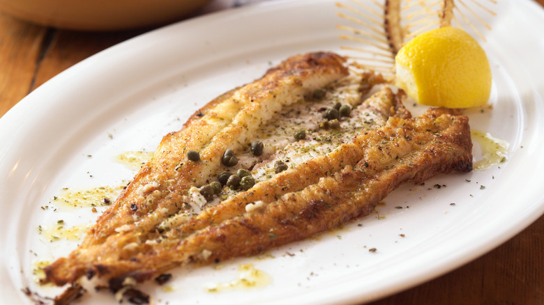 Filet of dover sole with capers, lemon and bone as garnish.