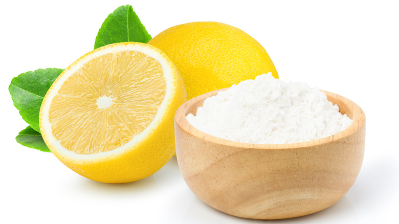 bowl of baking soda and cut lemon on a white background