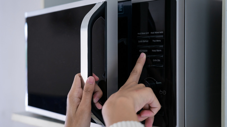 two hands shutting microwave