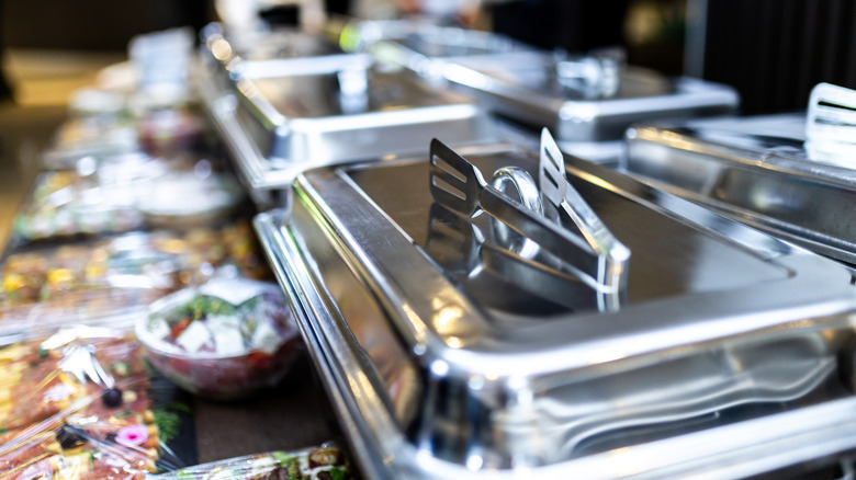 A pair of tongs rests on a closed buffet tureen