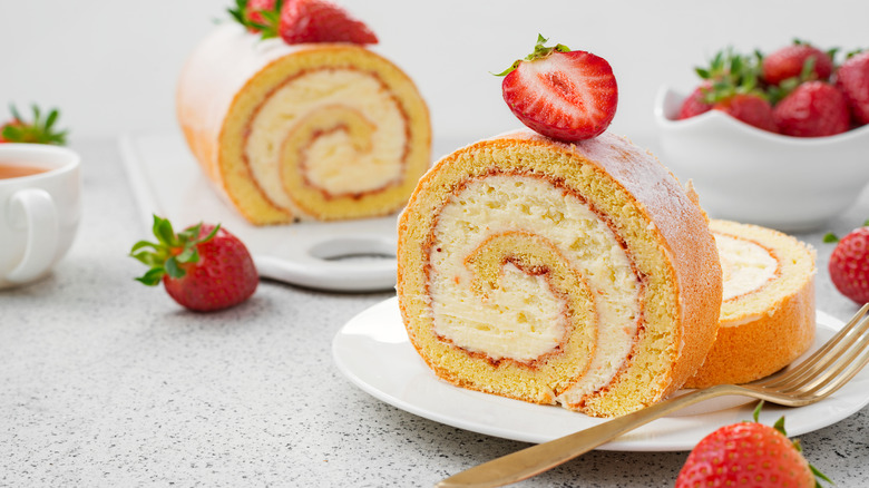 Slice of a roll cake on plate with strawberries