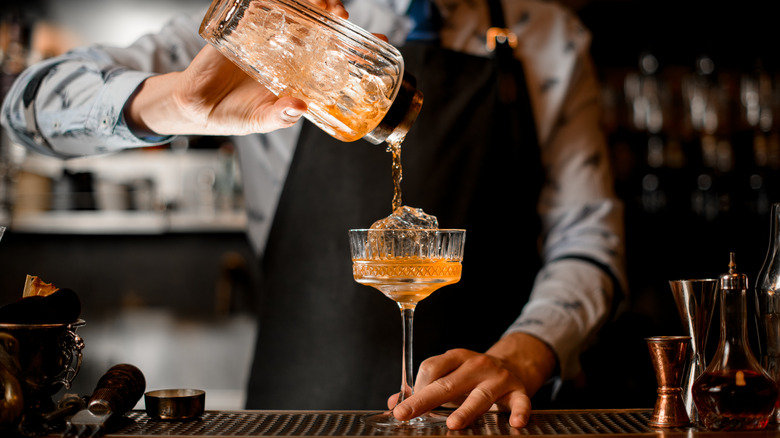 A bartender pours out a cocktail