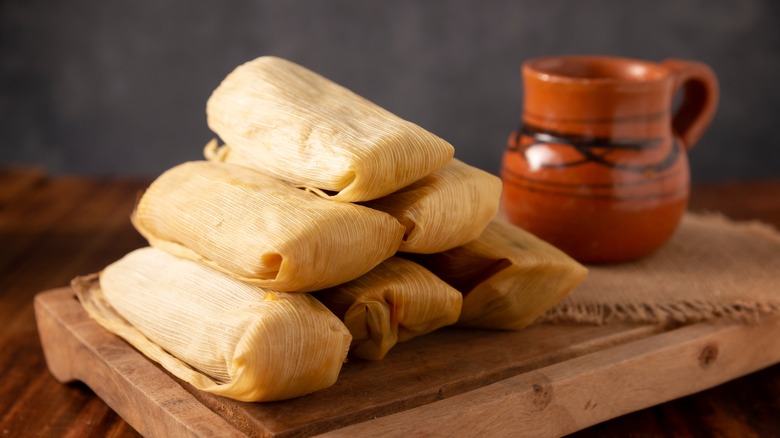 Tamales stacked on a wooden board
