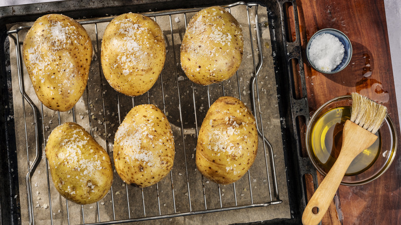Overhead shot of salt crusted baked potatoes on an oven rack