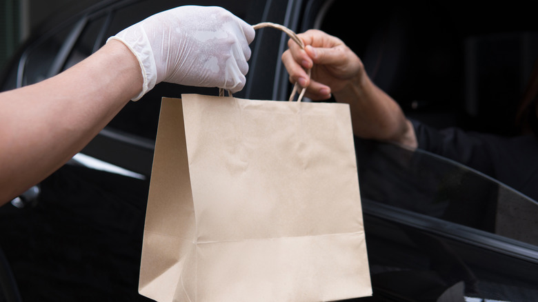 Drive-thru worker handing bag to customer