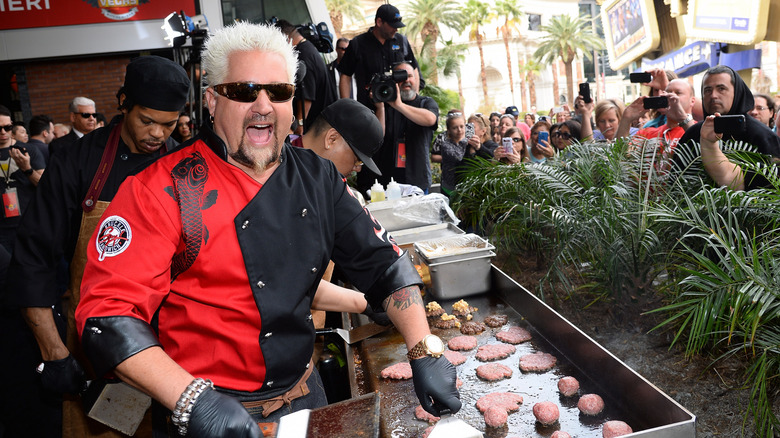 Guy Fieri cooking burgers on an outdoor flat top