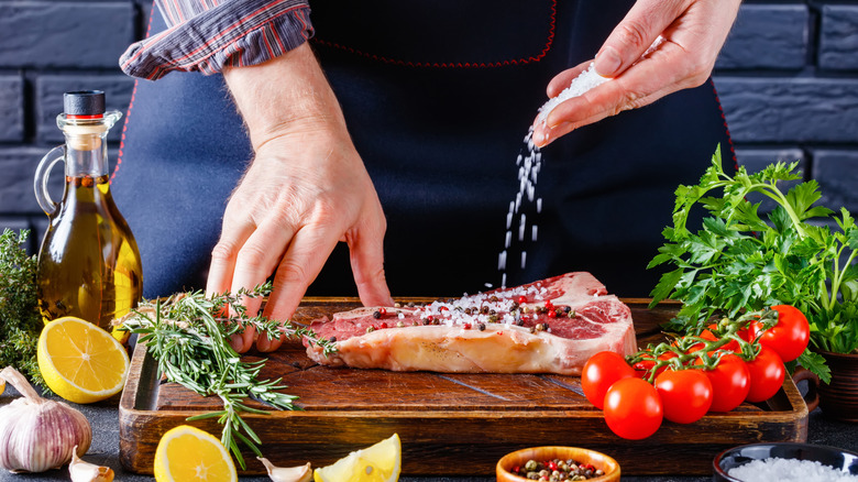 Hands salting a steak