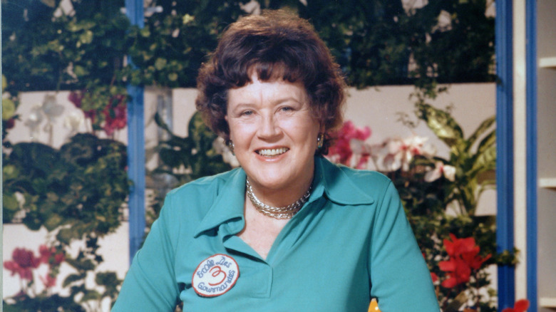 Julia Child in front of a fence and flowers