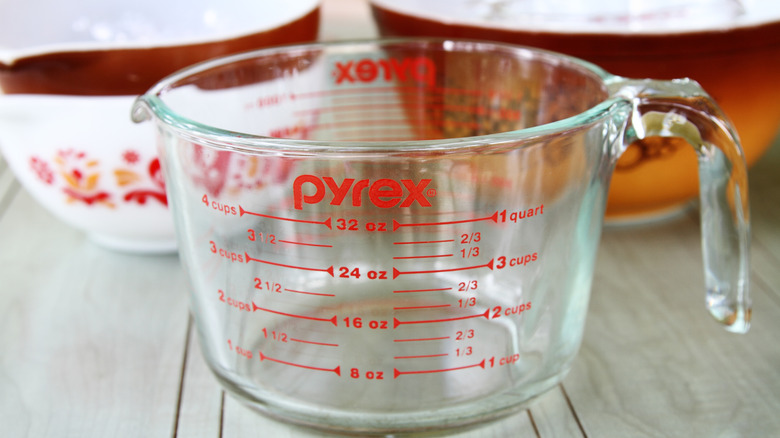 Clear Pyrex measuring cup with Pyrex mixing bowls in the background
