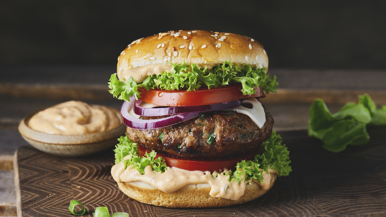 Burger on a cutting board with toppings