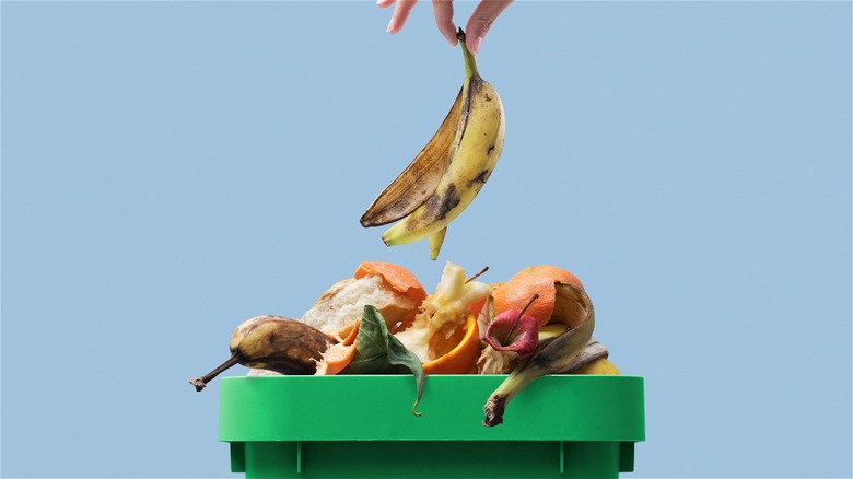 Hand dropping banana peel in garbage