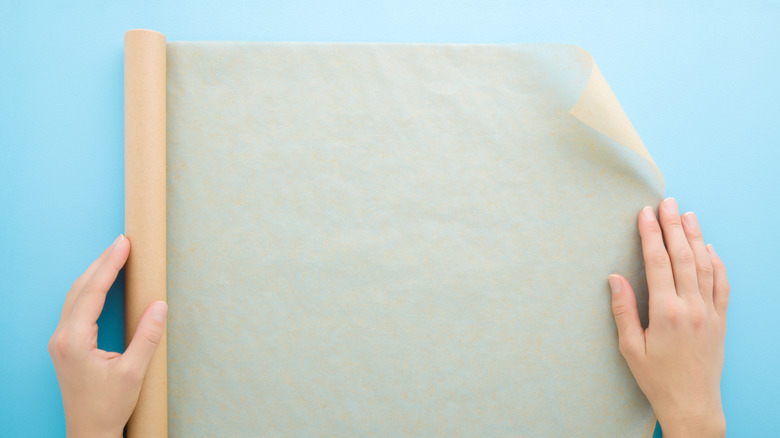 Person unrolling parchment paper