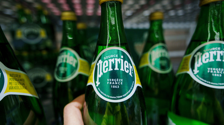 A person holds a bottle of Perrier sparkling water