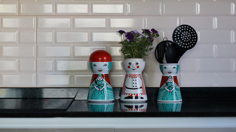 Three decorative utensil crocks shaped like women in dresses and a chef