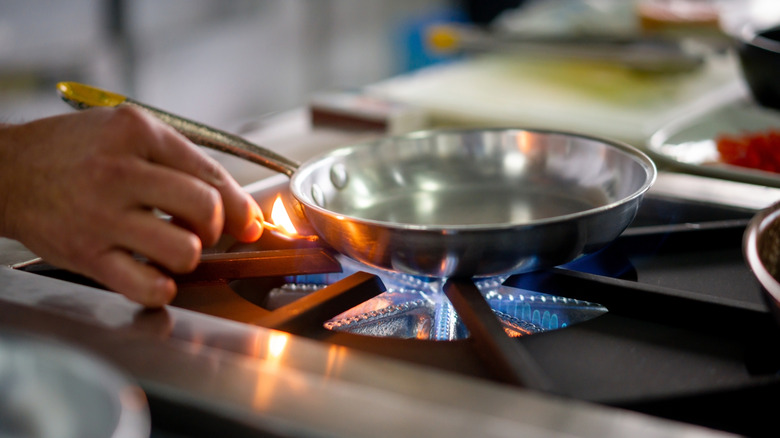 lighting a burner under pan