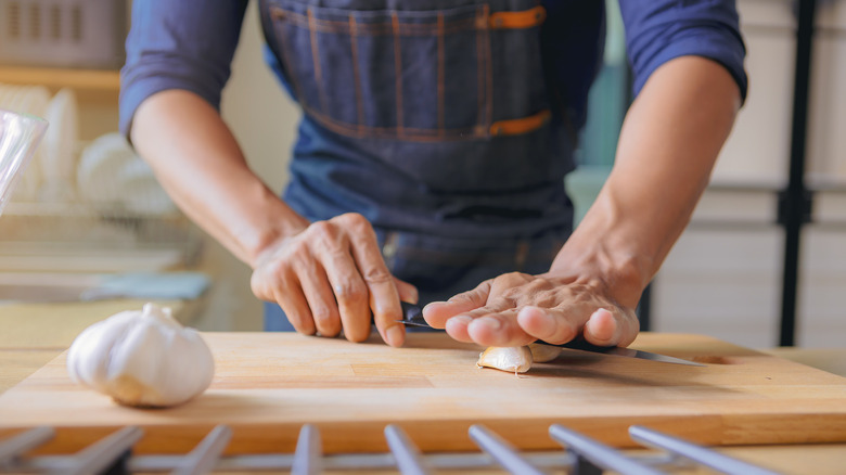 Person crushing garlic with knife