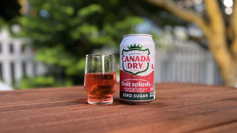 Can of Fruit Splash Zero Sugar Ginger Ale; glass filled next to it on wooden table outdoors