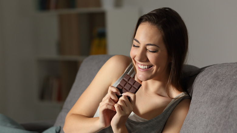 Woman laughing while eating dark chocolate