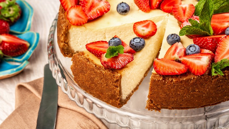 whole cheesecake on cake stand topped with berries