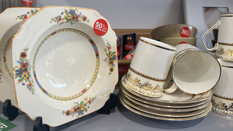 Dinnerware with discount stickers sitting on a thrift store shelf