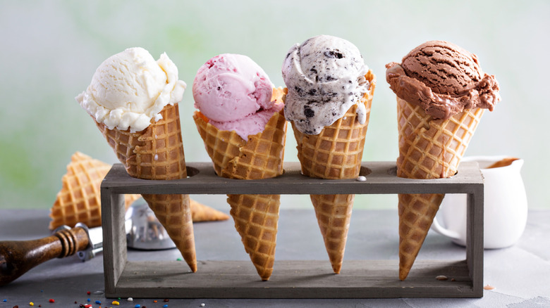 Four waffle ice cream cones in stand with different ice creams