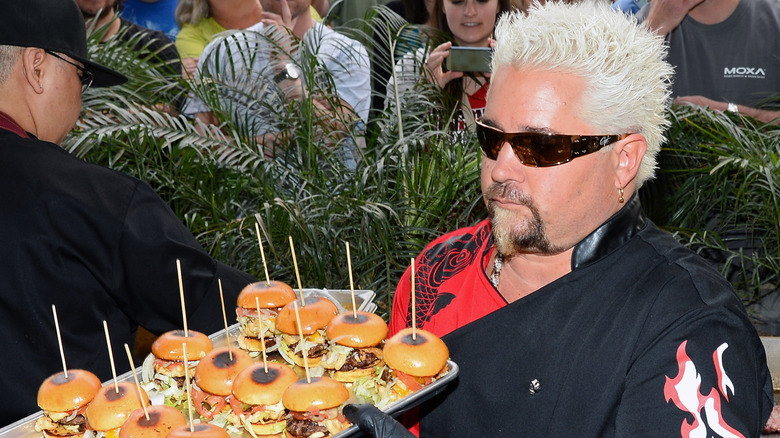 guy fieri holding a tray of burgers
