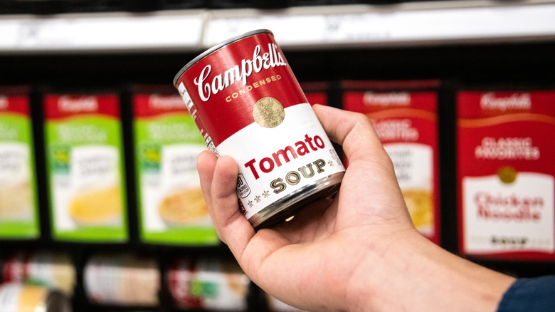 holding out can of tomato soup in grocery store